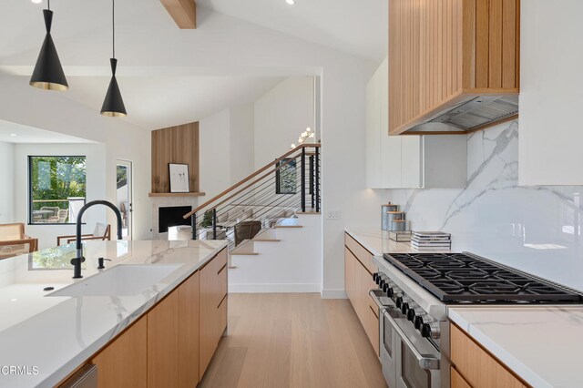 kitchen with range with two ovens, light hardwood / wood-style floors, sink, and light stone countertops