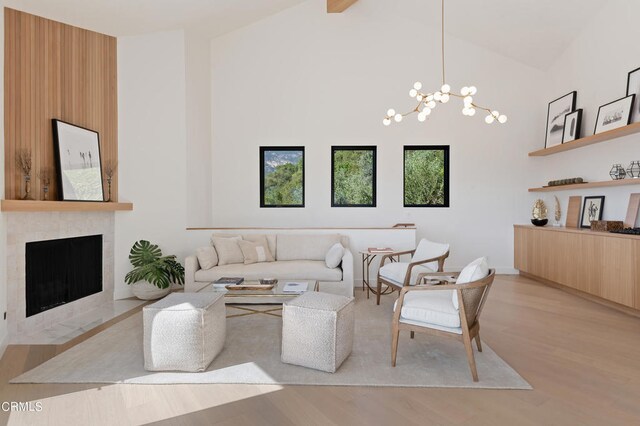 living room with a fireplace, high vaulted ceiling, hardwood / wood-style flooring, and a chandelier