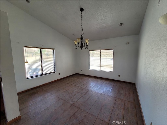 unfurnished dining area with a chandelier, vaulted ceiling, and hardwood / wood-style flooring