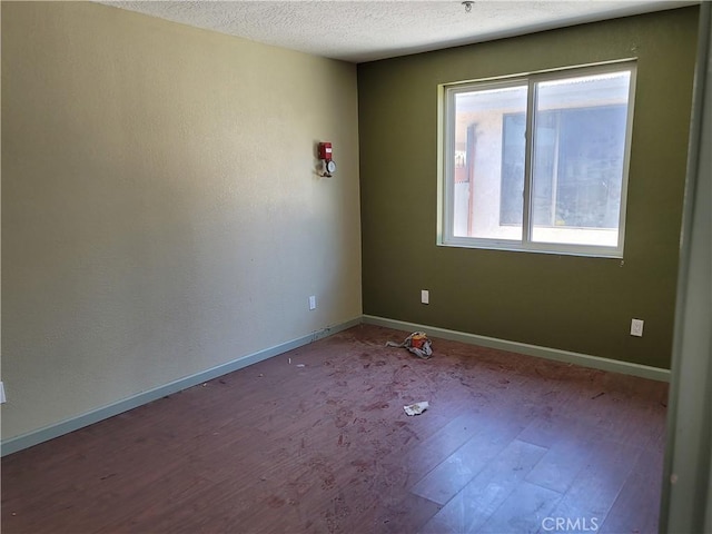 spare room featuring wood-type flooring and a textured ceiling