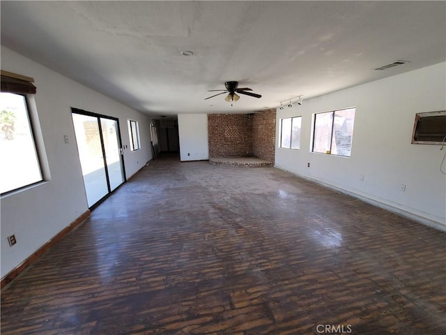 empty room featuring dark hardwood / wood-style floors, ceiling fan, and a brick fireplace