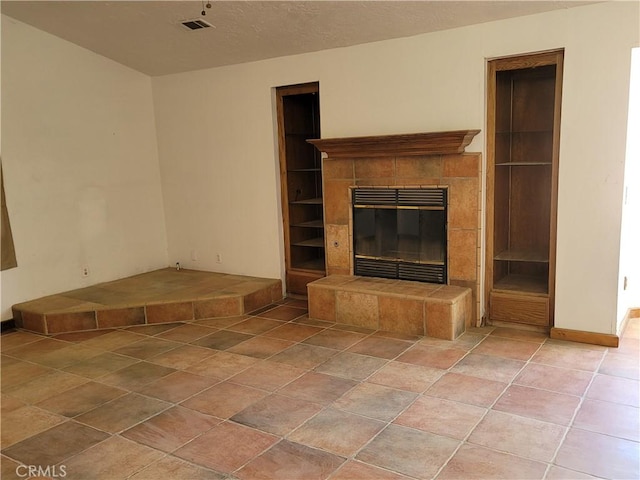 unfurnished living room with a tile fireplace and a textured ceiling