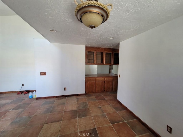 interior space with a textured ceiling and dark tile patterned floors