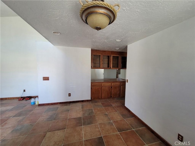 31801 Soapmine Rd, Barstow, CA 92311 - kitchen with brown cabinets, a textured ceiling, and glass insert cabinets