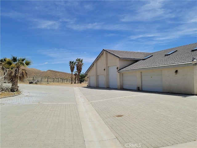 31801 Soapmine Rd, Barstow, CA 92311 - view of side of home with stucco siding, driveway, a tiled roof, and an attached garage