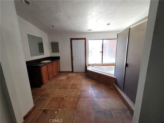 bathroom featuring tile patterned floors, tiled bath, vaulted ceiling, a textured ceiling, and vanity