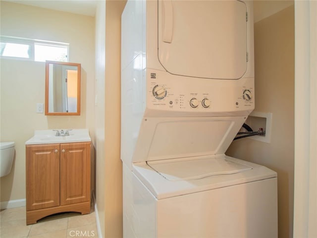 clothes washing area with stacked washer and dryer, light tile patterned floors, and sink