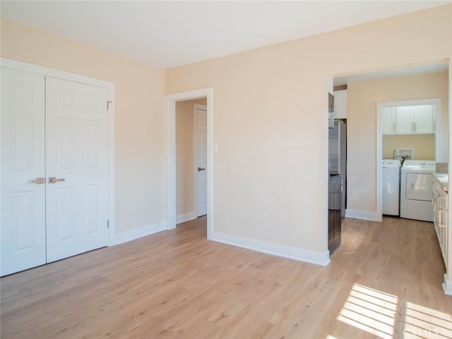 unfurnished bedroom featuring washing machine and dryer, a closet, and light wood-type flooring