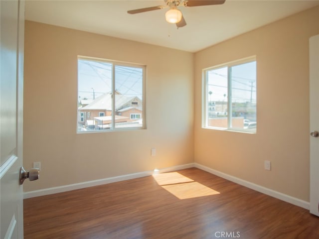empty room featuring plenty of natural light, ceiling fan, and dark hardwood / wood-style flooring
