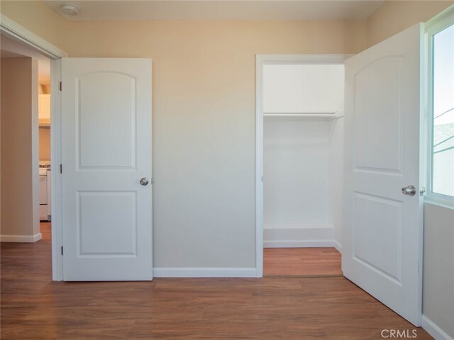 unfurnished bedroom with multiple windows, a closet, and hardwood / wood-style flooring