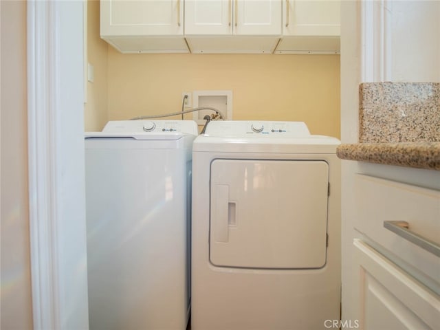clothes washing area featuring cabinets and washer and clothes dryer