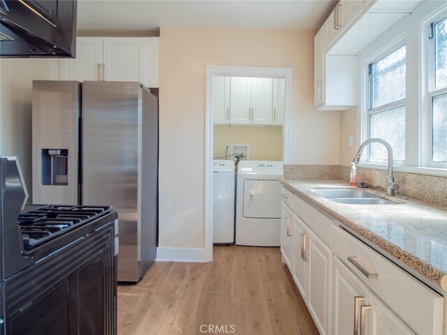 kitchen featuring white cabinets, light hardwood / wood-style flooring, washer and dryer, and sink