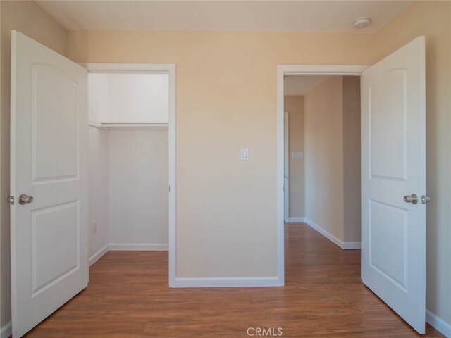 unfurnished bedroom with dark hardwood / wood-style flooring and a closet