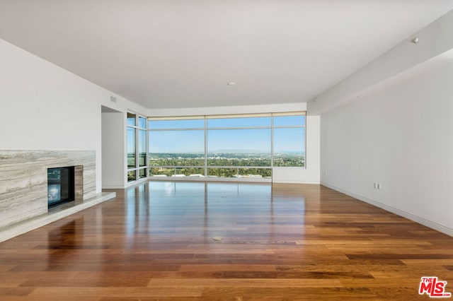 unfurnished living room featuring a wall of windows, a fireplace, and hardwood / wood-style flooring