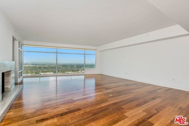 unfurnished living room with hardwood / wood-style flooring, floor to ceiling windows, and a high end fireplace