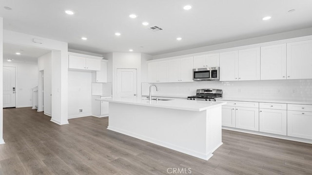 kitchen with white cabinetry, appliances with stainless steel finishes, sink, and a center island with sink