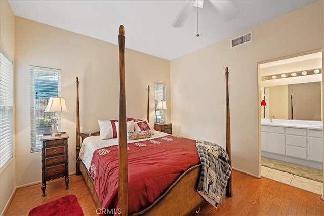 bedroom featuring visible vents, ensuite bath, a ceiling fan, and wood finished floors