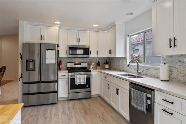 kitchen with light countertops, white cabinets, appliances with stainless steel finishes, and a sink