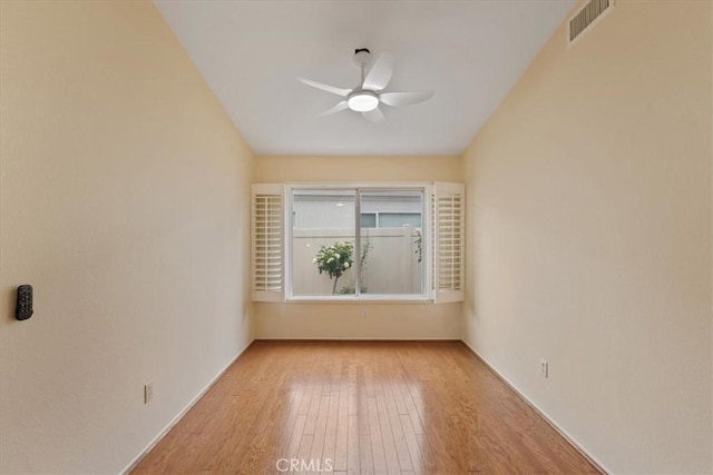 unfurnished room featuring visible vents, hardwood / wood-style floors, and a ceiling fan