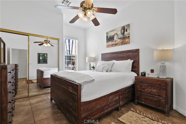 bedroom with ceiling fan, a closet, and dark tile patterned floors