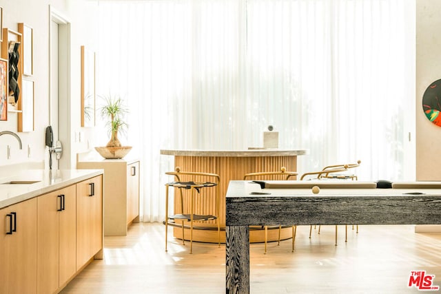 bar featuring sink, light brown cabinets, and light hardwood / wood-style flooring