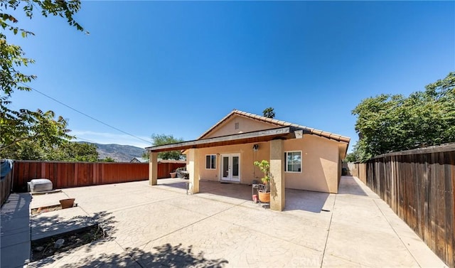 rear view of property with a patio area, a mountain view, and french doors