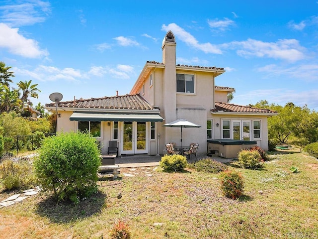 rear view of house with a hot tub, a yard, a patio area, and french doors