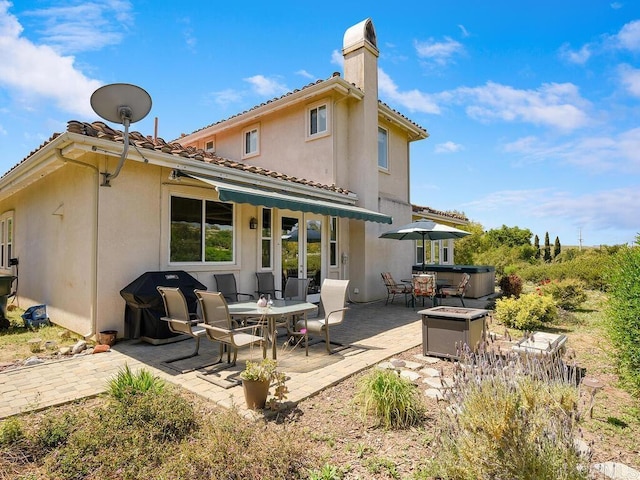 rear view of house featuring a hot tub and a patio