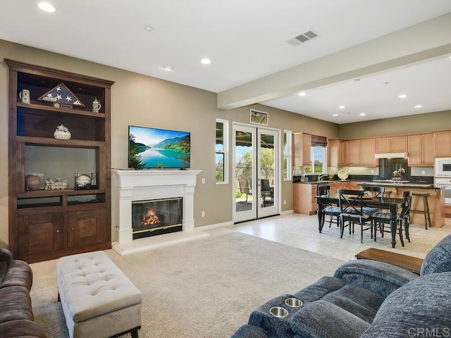 carpeted living room featuring beamed ceiling and french doors