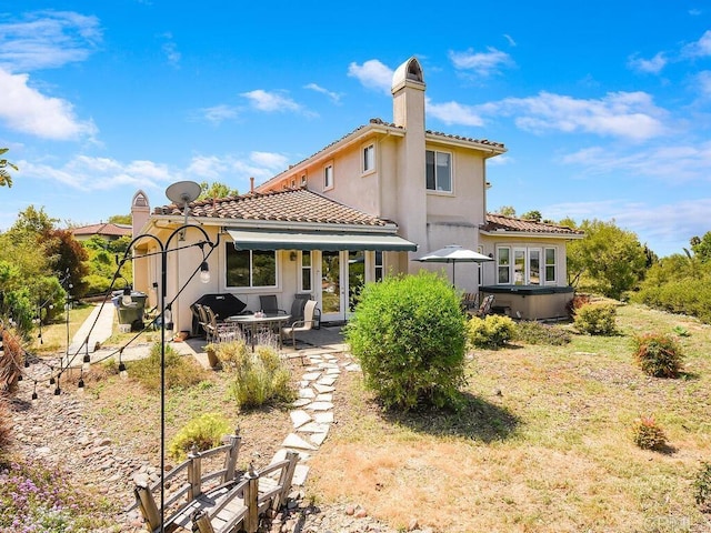 back of house featuring a hot tub and a patio