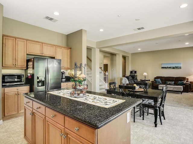 kitchen with a center island, stainless steel fridge, and dark stone counters