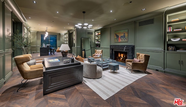 living room featuring dark parquet flooring, an inviting chandelier, crown molding, built in features, and a fireplace