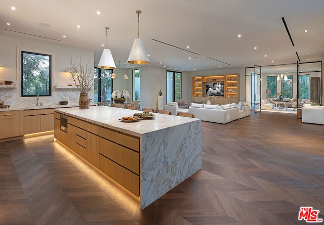 kitchen with dark parquet floors, tasteful backsplash, a wealth of natural light, and a large island