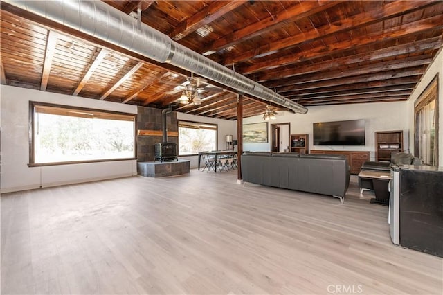 unfurnished living room with lofted ceiling with beams, light hardwood / wood-style floors, a wood stove, and wood ceiling