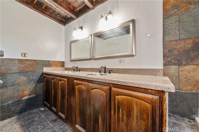 bathroom featuring vanity, beamed ceiling, and tile walls