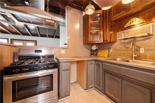 kitchen with stainless steel gas stove, decorative backsplash, light wood-type flooring, and sink