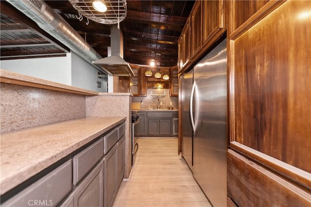 kitchen featuring decorative backsplash, stainless steel appliances, sink, light hardwood / wood-style floors, and range hood