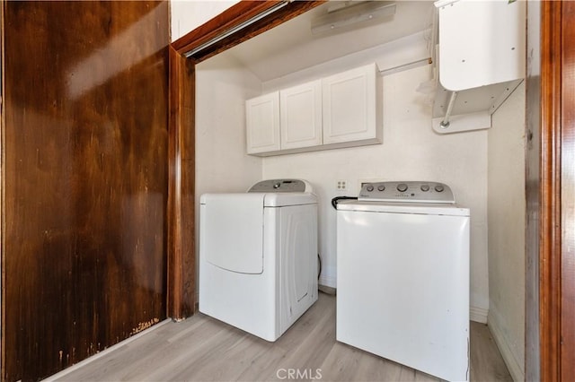 laundry room featuring cabinets, washer and clothes dryer, and light hardwood / wood-style floors