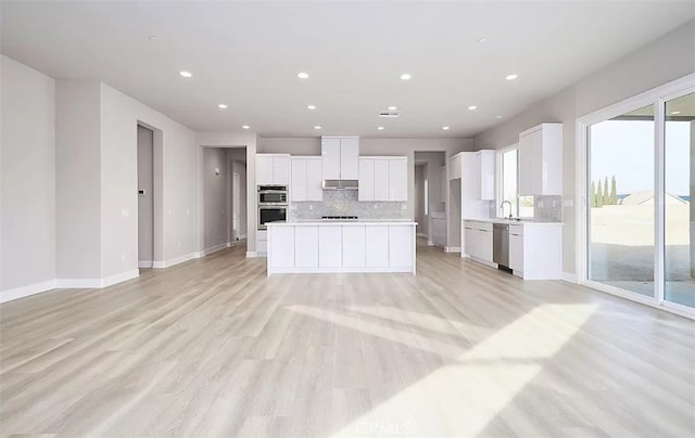 kitchen featuring white cabinets, a center island, light wood-type flooring, and stainless steel appliances