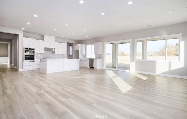 kitchen featuring white cabinets, a center island, stainless steel appliances, and light hardwood / wood-style flooring