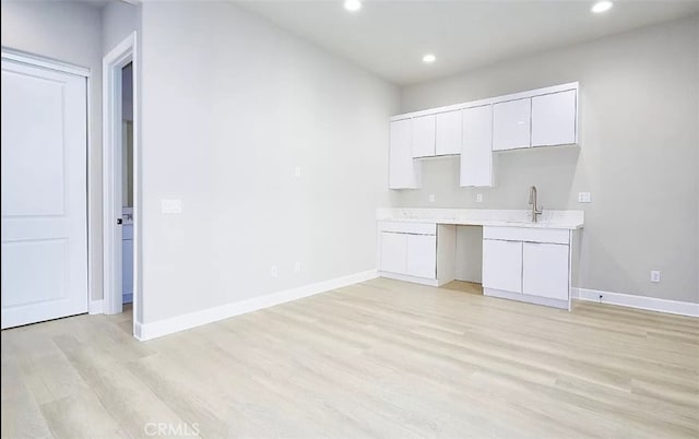 kitchen featuring light hardwood / wood-style flooring, white cabinetry, and sink