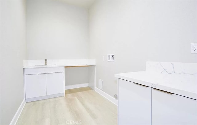 washroom with cabinets, sink, hookup for a washing machine, and light hardwood / wood-style flooring