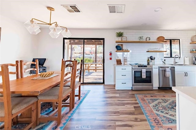 kitchen with white cabinetry, appliances with stainless steel finishes, hardwood / wood-style flooring, sink, and tasteful backsplash