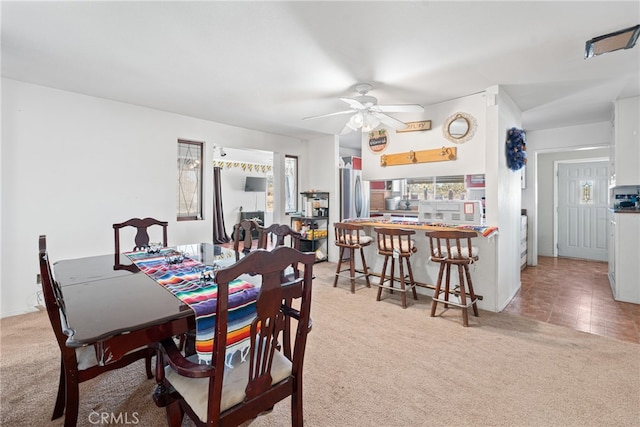 dining area with ceiling fan and light colored carpet