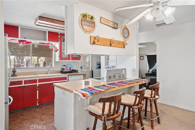 kitchen with sink, wood counters, stainless steel fridge, dark carpet, and a breakfast bar