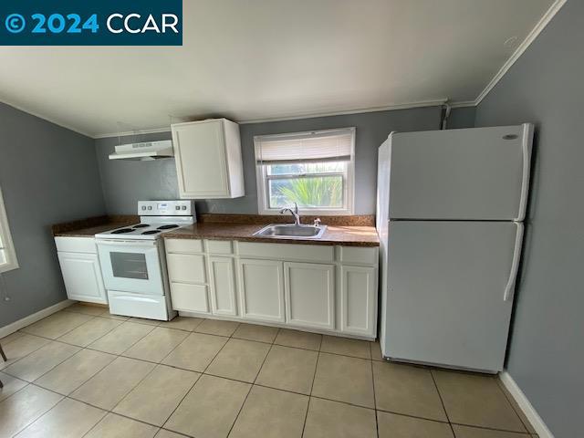 kitchen with white cabinets, white appliances, sink, and light tile flooring