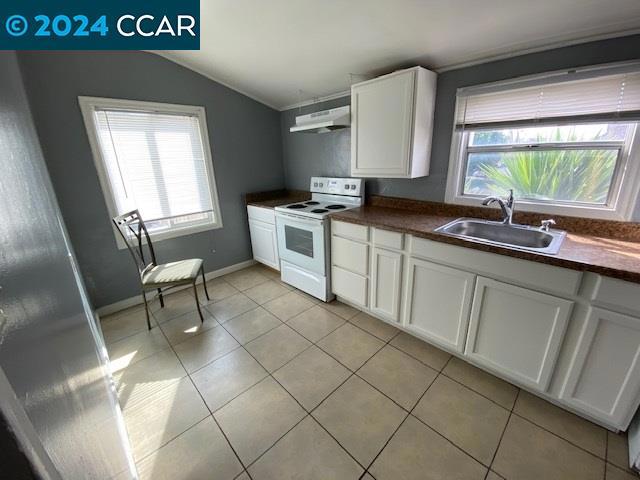 kitchen featuring plenty of natural light, electric stove, sink, and lofted ceiling