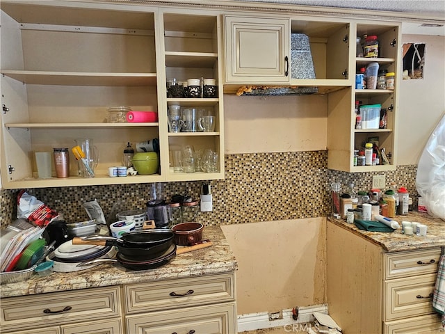 kitchen with cream cabinetry, decorative backsplash, and light stone counters