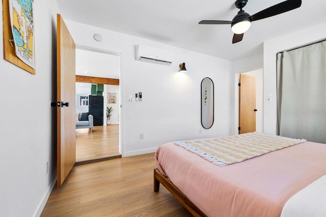 bedroom featuring a wall unit AC, ceiling fan, and light wood-type flooring