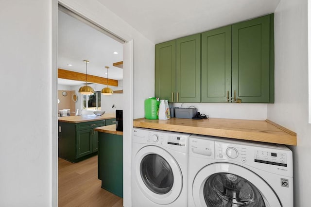 laundry area with washing machine and dryer, light hardwood / wood-style flooring, and cabinets